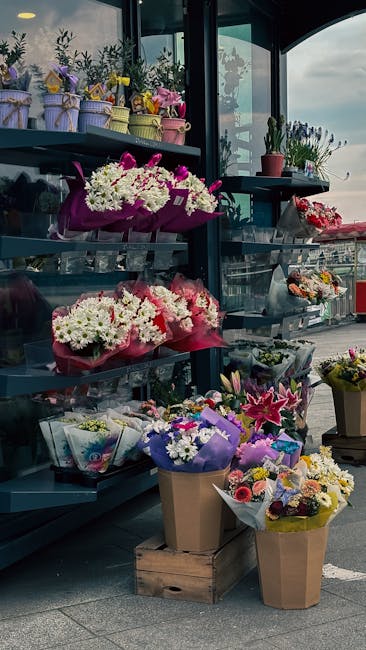 A display of various floral arrangements and bouquets at a flower shop, with a focus on fresh flowers including white, pink, and purple blooms. The arrangements are wrapped in colorful paper and place
